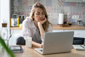 Woman searching for health insurance in her kitchen on her laptop.