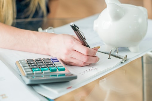 Girl writing in her budget notebook. Trying to work in Healthcare Insurance.